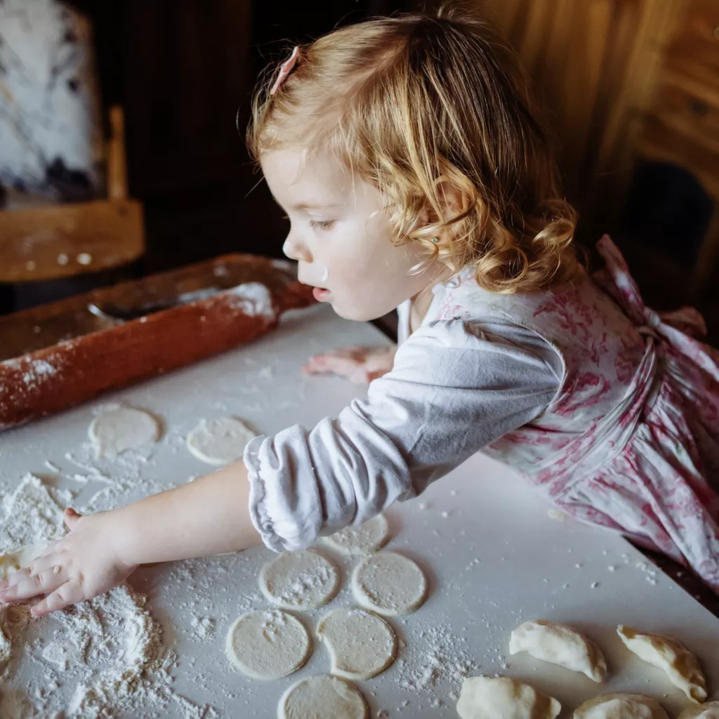 A young girl playing with flour as she tries to prepare a dessert of some kind.