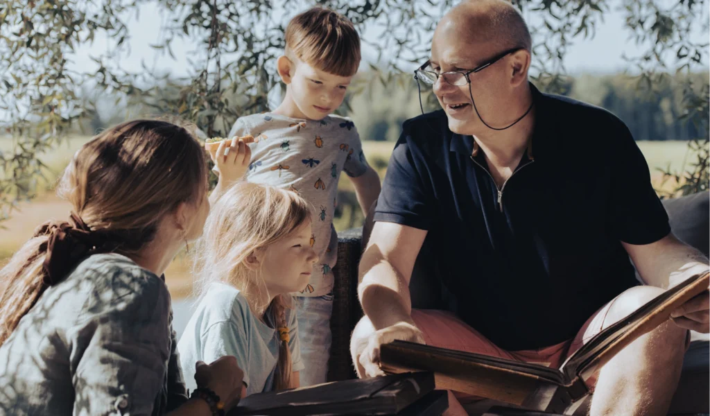 A family history journal being shown to children by their grandparent