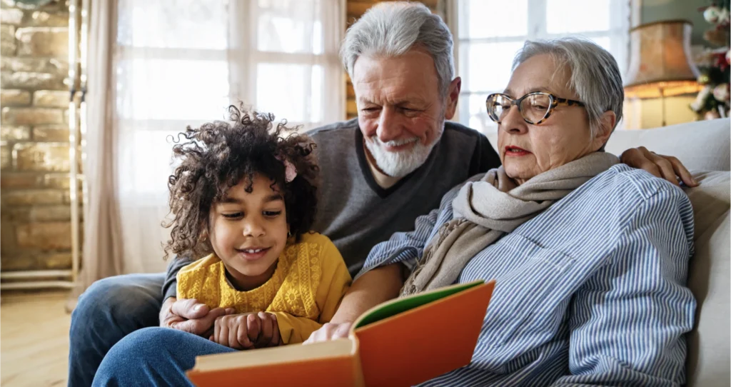 Grandparents looking through a family stories memory book with their granddaughter 