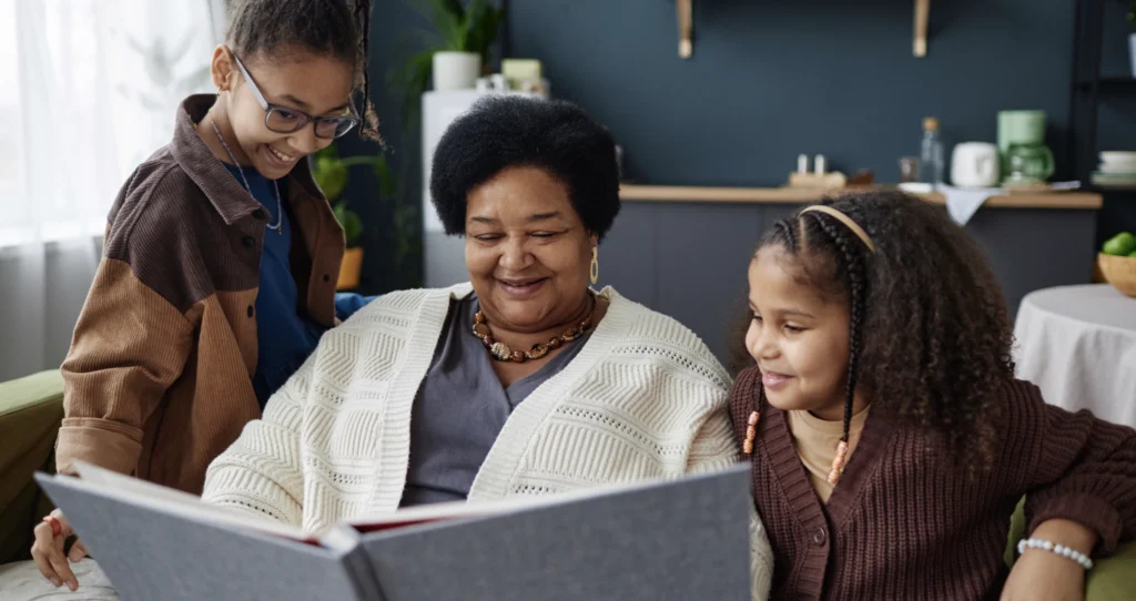 A grandmother with her granddaughters, looking at their Family memory journal