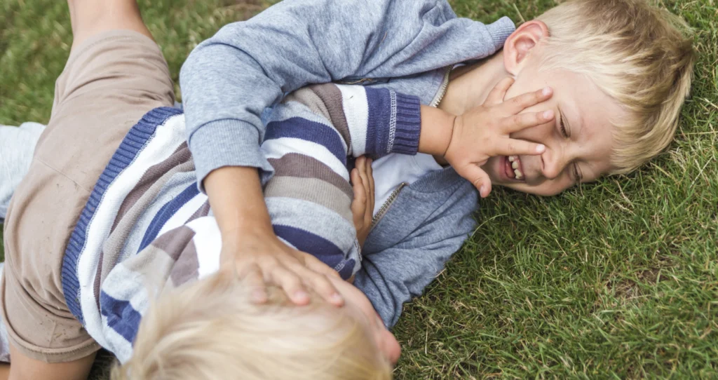 Too young boys fighting each other on the grass