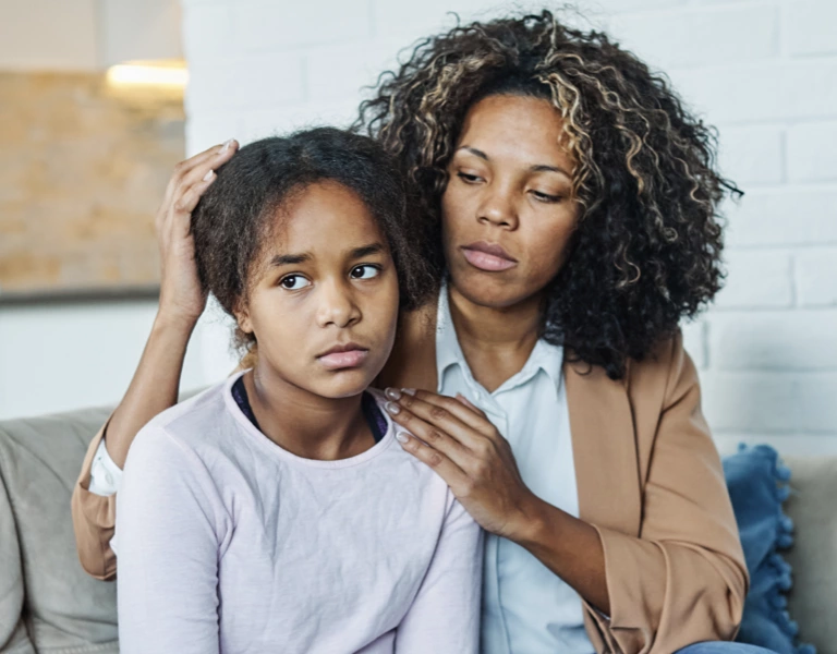 A daughter looking upset with her mother trying to console her.