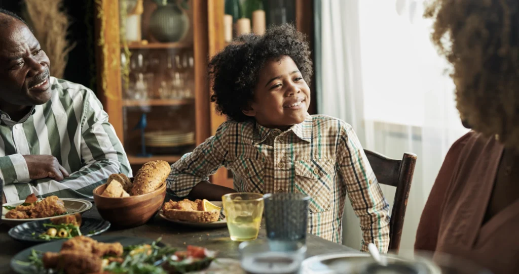 A young boy talking with his parents over a Sunday dinner.