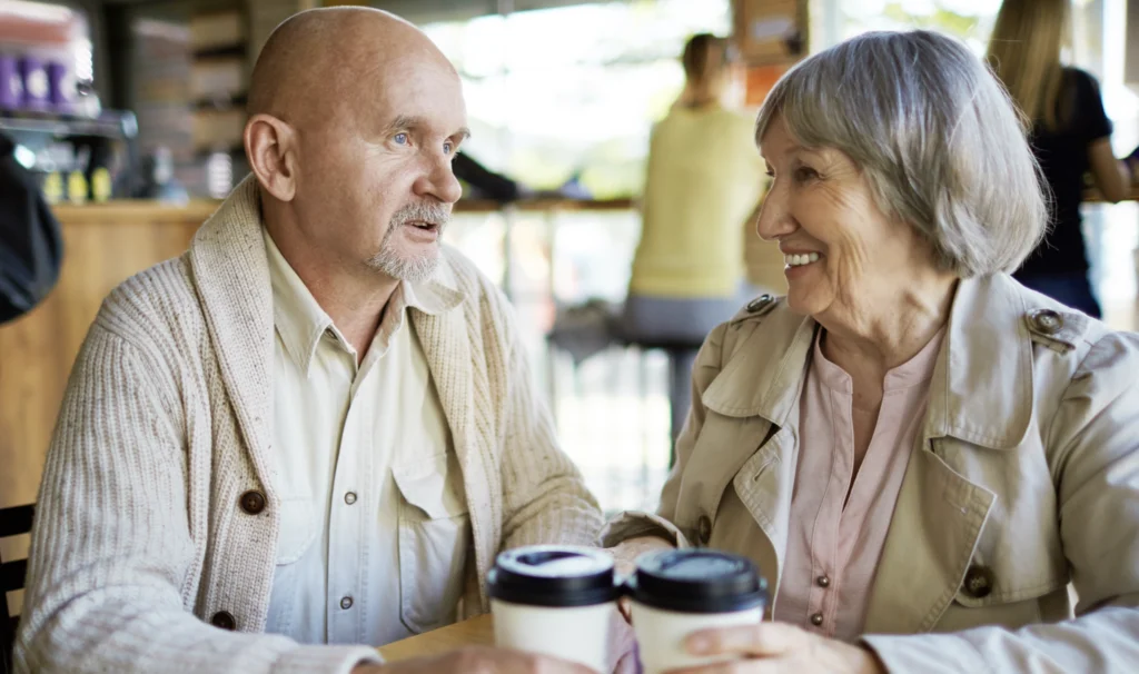 An elderly couple having a conversation over coffee. 