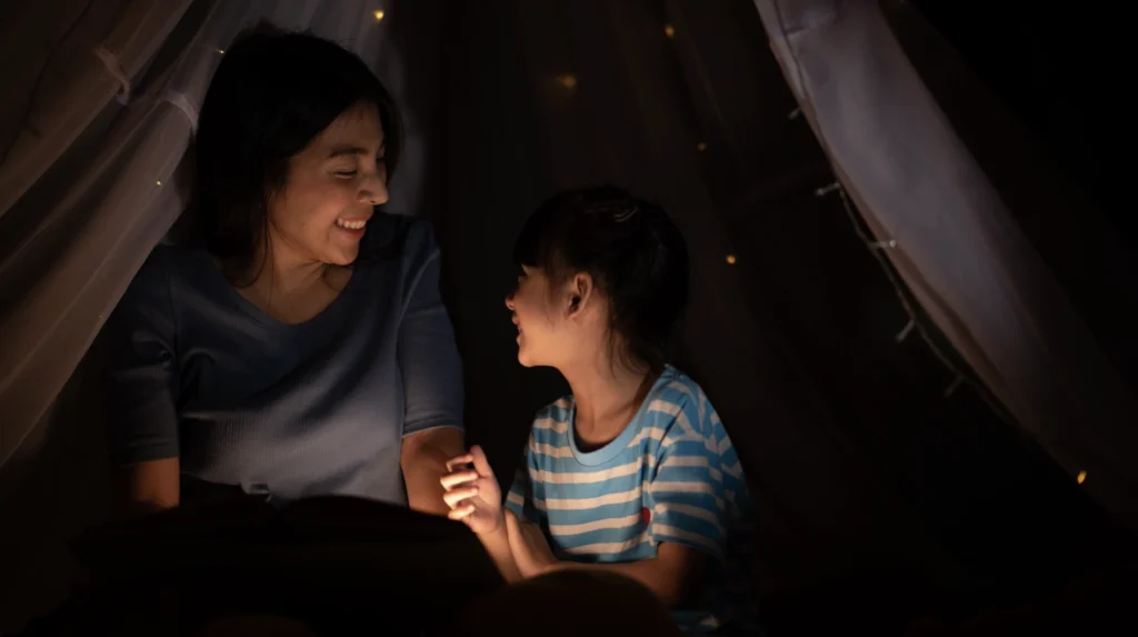 A mother with her daughter having a wind-down conversation before she goes to bed.