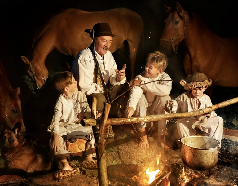 A old photo of a man telling stories to children around a fire
