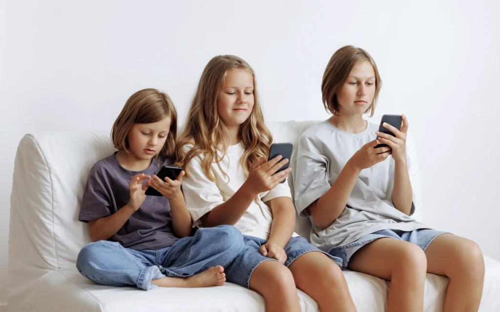 Three siblings all distracted as they look at their digital devices 