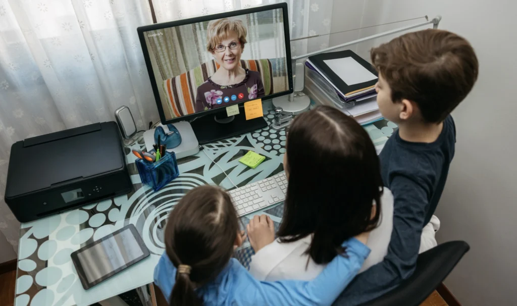 A single-parent with her children on a video call with a grandmother