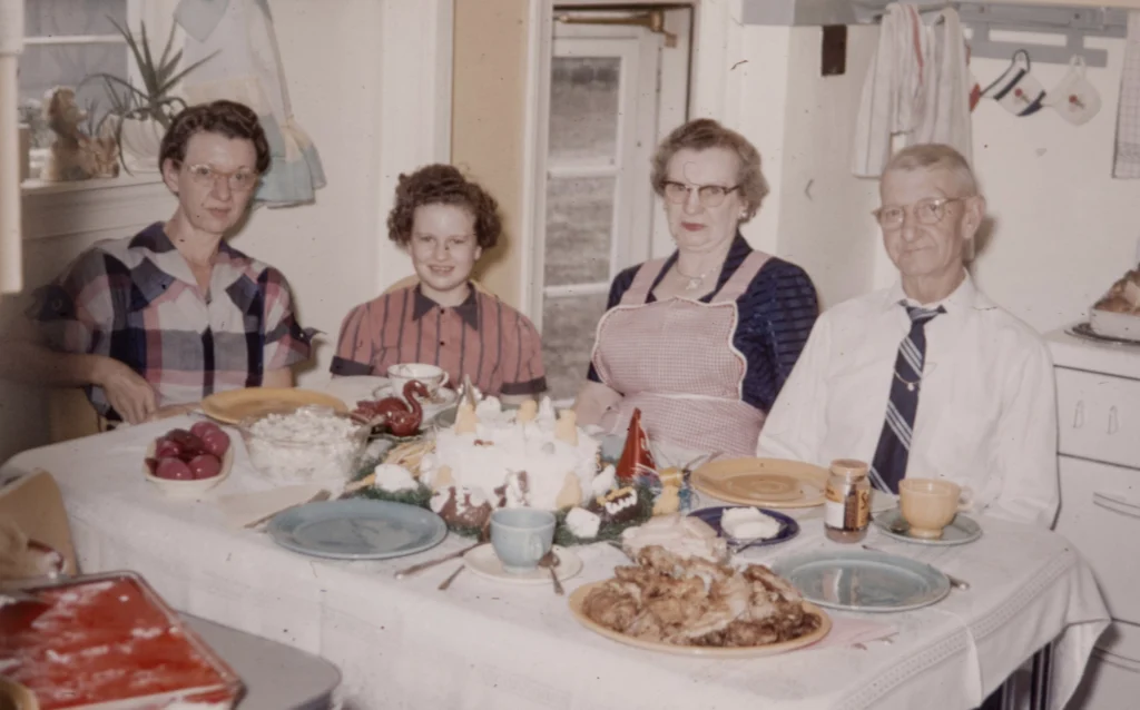 An old photo of a family sitting down to an elaborate dinner. 