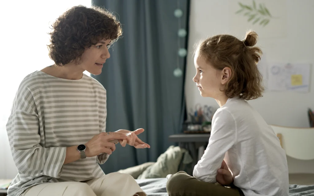 A mother having an honest conversation with her young daughter, illustrating how honesty and integrity are modelled and taught within families.