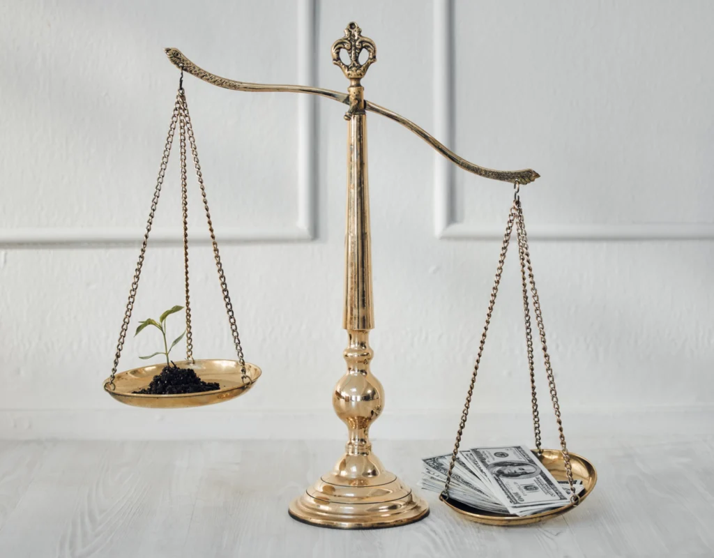 A traditional scale, weighing money against a growing plant