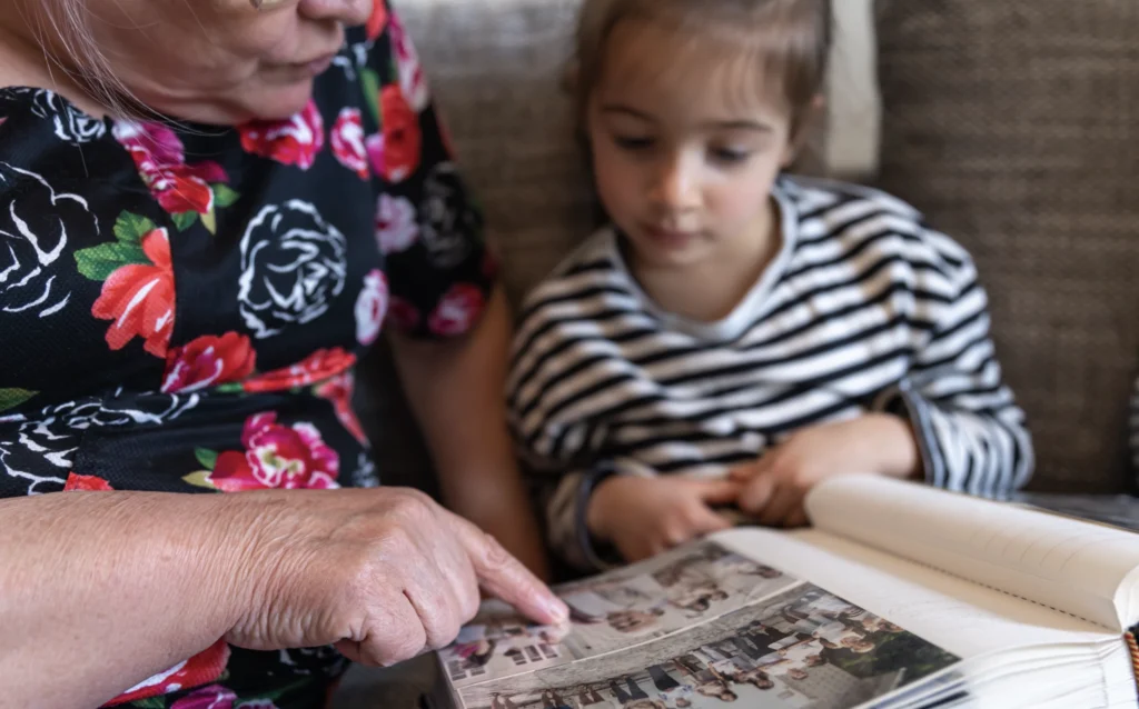 A grandmother showing her granddaughter photos from the past and sharing the stories behind them. 