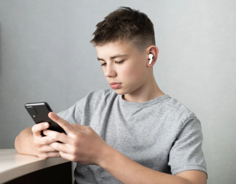 A teenager on his summer holidays playing indoors on his phone